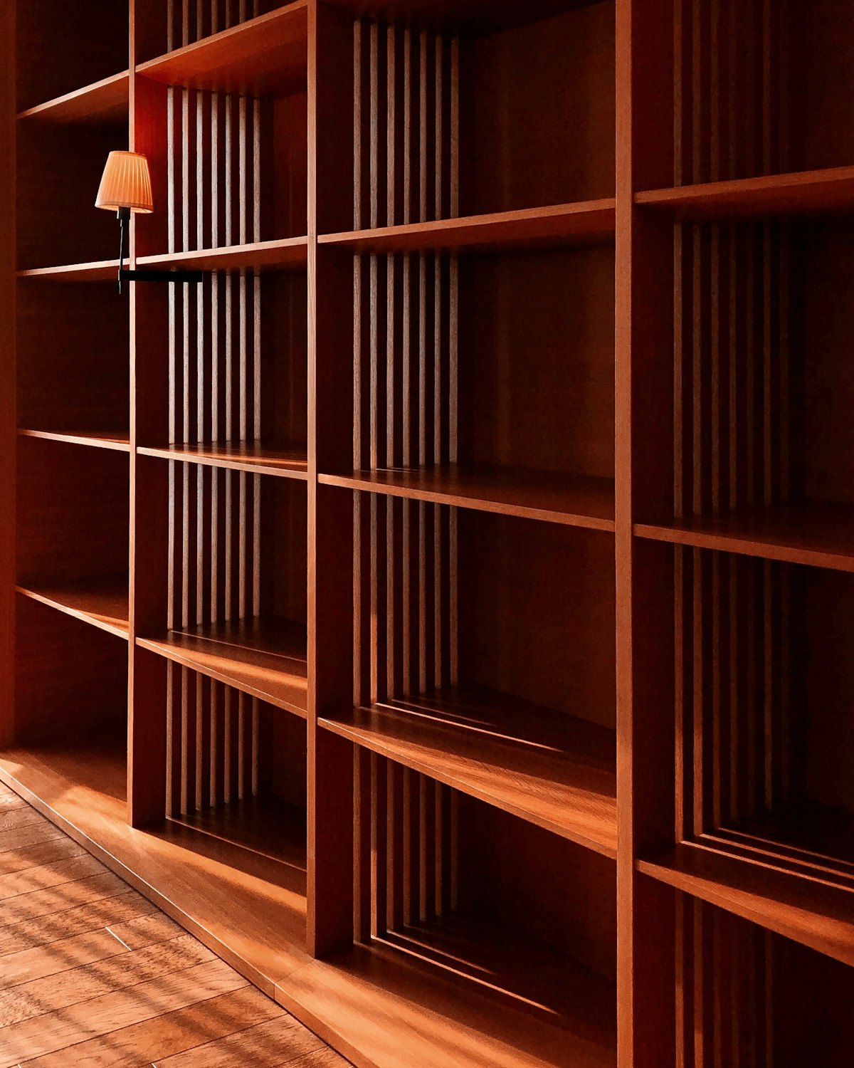 A wall of rich timber shelving with a pendant lamp