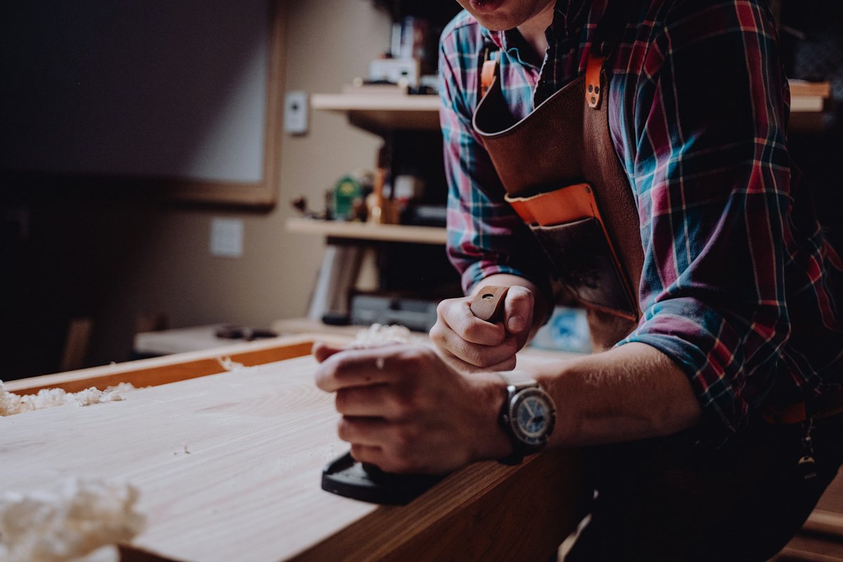 Hands shaping a piece of timber at a workbench